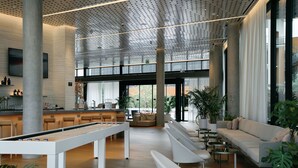 Un hall espacioso con mesa de billar, zona de estar y grandes ventanales.