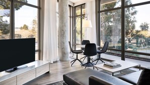 Una sala de estar moderna con un televisor grande, asientos cómodos y ventanas amplias que ofrecen vistas al exterior.