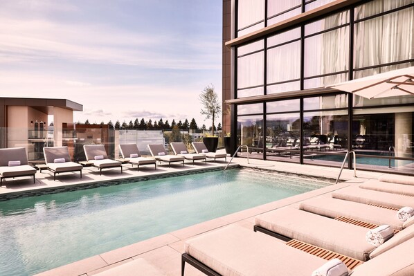 Ein moderner Poolbereich mit Liegestühlen und Blick auf die Stadt.