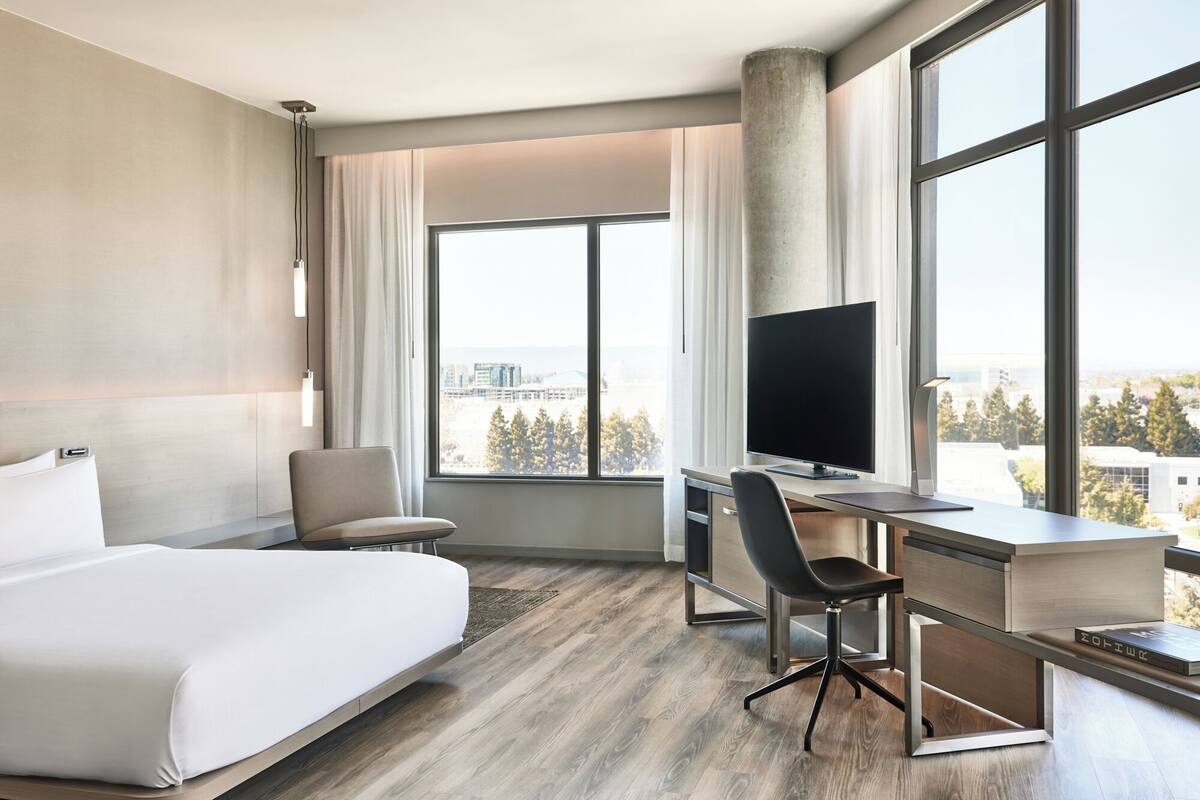 Une chambre d’hôtel moderne avec un grand lit, un bureau équipé d’un ordinateur et une télévision.