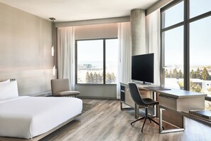 Ein modernes Hotelzimmer mit einem großen Bett, einem Schreibtisch mit Computer und einem Fernseher.
