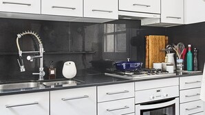 Een moderne keuken met witte kastjes, een zwart aanrecht, een roestvrijstalen spoelbak en een inbouwoven.