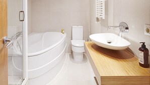 Een moderne badkamer met een vrijstaand bad, toilet en een wastafel met een houten aanrechtblad.