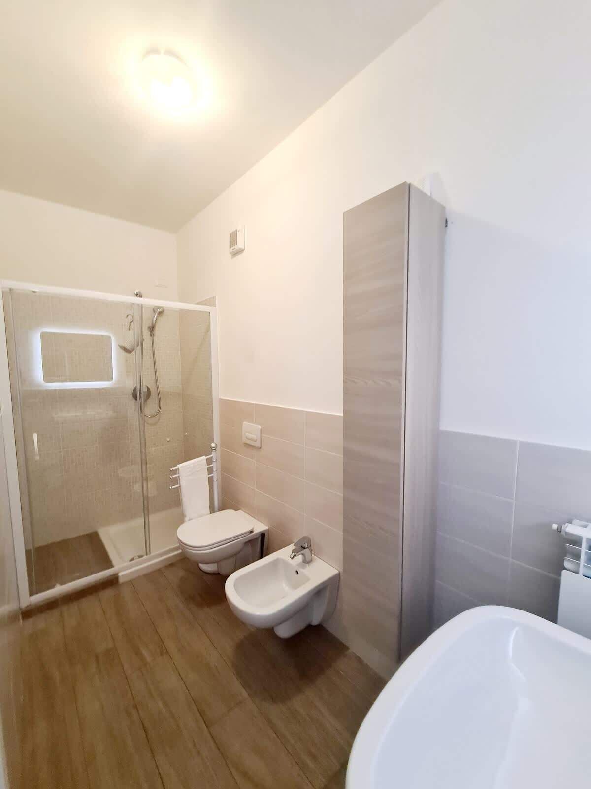 Un bagno moderno con doccia vetrata, WC, bidet e vasca da bagno.