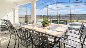 A covered patio with a table set for dining, chairs, a ceiling fan, and a view of a swimming pool and neighborhood. - WIR Free Pool Heat/Grill Use, Walk to Lazy River (Four Corners)