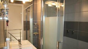 Ein modernes Badezimmer mit Duschkabine aus Glas, einem weißen Waschbecken und einem Spiegel.