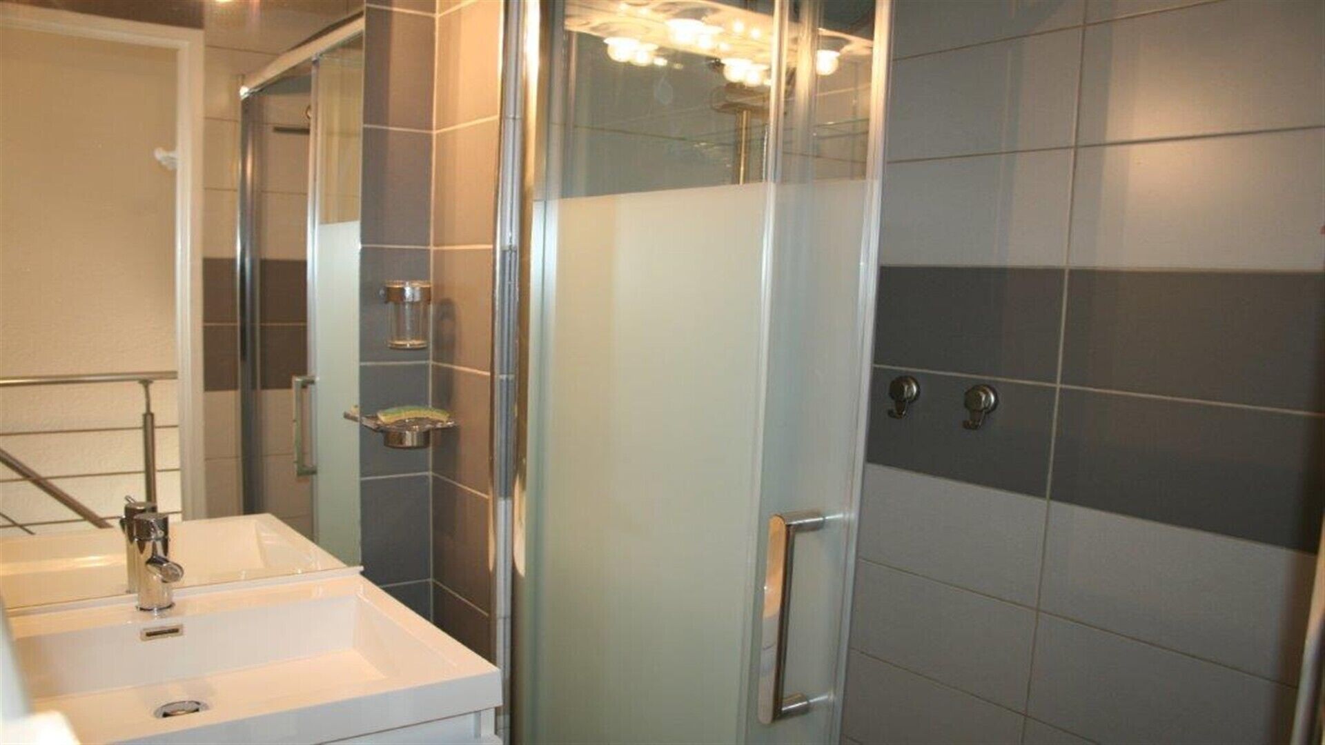 Une salle de bain moderne avec une douche à parois de verre, un lavabo blanc et un miroir.