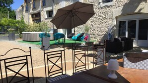 An outdoor seating area with a table, chairs, and a large umbrella. - LOFT P'TITE POMME with SPA (Azay-le-Rideau)