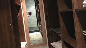 A narrow hallway with wooden shelving units on both sides, a small mirror, and a light fixture on the ceiling. - LOFT P'TITE POMME with SPA (Azay-le-Rideau)
