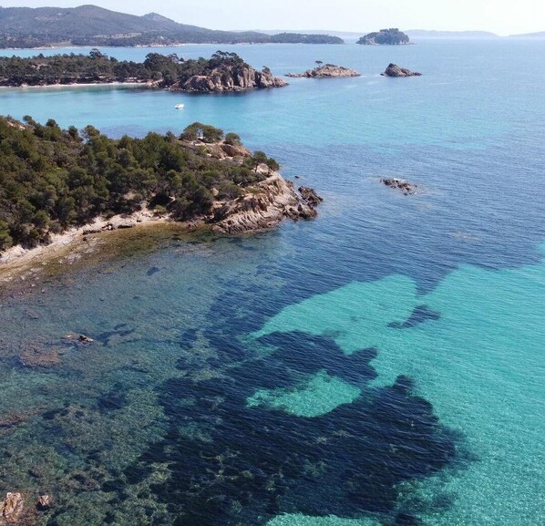 Un paisaje costero con aguas turquesas cristalinas, afloramientos rocosos y abundante vegetación.