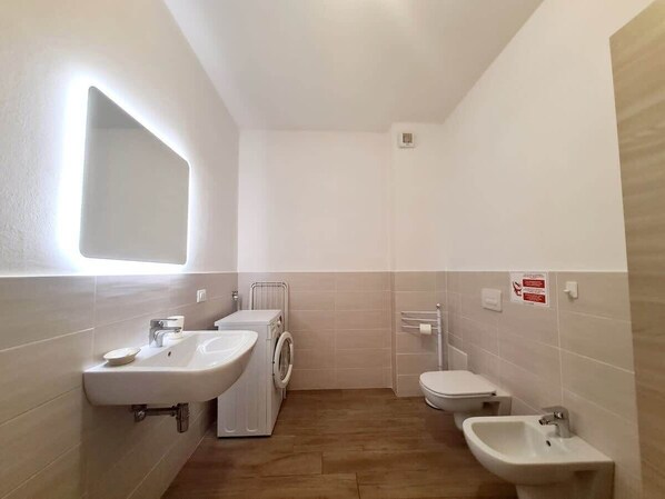 Une salle de bain équipée d’un lavabo, de toilettes, d’un bidet et d’un lave-linge.