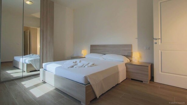 A modern bedroom with a large bed, bedside tables, a wardrobe, and a door. - Balcony Condo Steps to Beach & Train Station - O (Levanto)