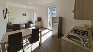 A modern kitchen with a dining area, a refrigerator, a stove, and a sink. - Balcony Condo Steps to Beach & Train Station - O (Levanto)