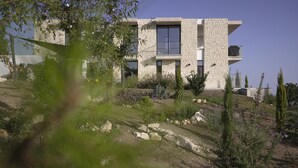 Ein modernes Gebäude mit einer Stein-Fassade, mehreren Balkonen und einem angelegten Garten.