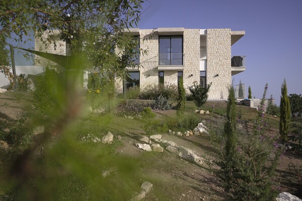 Un edificio moderno con fachada de piedra, varios balcones y un jardín ajardinado.