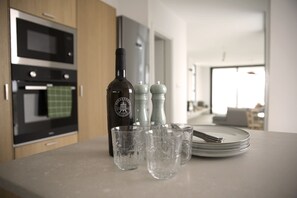 Una encimera de cocina con una botella de vino, saleros y pimenteros, y vasos vacíos.