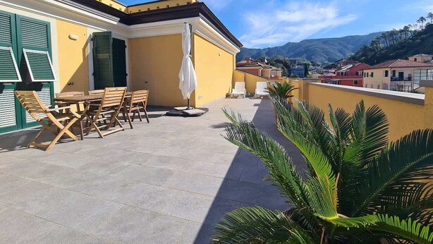 A rooftop terrace with a table and chairs, a white umbrella, and a view of the surrounding buildings and mountains. - Levanto Condo w/ Terrace, Near Beach & Train  P (Levanto)