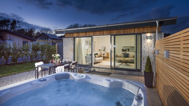 A modern house with a hot tub, a dining area, and a living room with a large window. - Footsteps to the dunes - Hot Tub - Pet friendly (Hayle)
