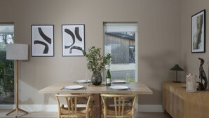 A dining area with a wooden table, two chairs, a vase with greenery, and framed abstract art on the wall. - Footsteps to the dunes - Hot Tub - Pet friendly (Hayle)