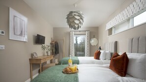A modern bedroom with two beds, a wooden desk, a TV, and a large window. - Footsteps to the dunes - Hot Tub - Pet friendly (Hayle)