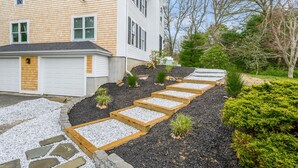 A residential property with a two-story house, a garage, and a landscaped garden with stepping stones and gravel paths.
