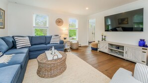 A living room with a blue sofa, a large flat-screen TV, and a wooden cabinet.