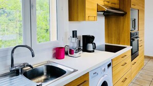 A modern kitchen with wooden cabinets, a stainless steel sink, a coffee maker, and a washing machine. - Beautiful apartment on 1st floor of a quiet villa in the countryside, near Ajaccio (Sarrola-Carcopino)
