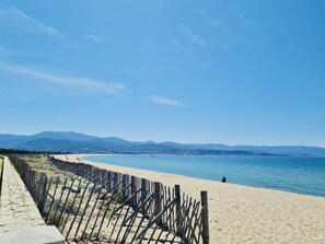 A beach with a wooden fence and a stone pathway.