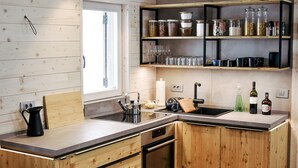 A modern kitchen with wooden cabinetry, a built-in oven, a sink, and a countertop with various kitchen items. - Private Cottage - Active Regeneration and Relaxing Hollidays (Stahovica)