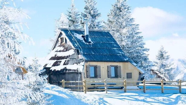 A rustic wooden cabin with a sloped roof, surrounded by snow-covered trees and a wooden fence. - Private Cottage - Active Regeneration and Relaxing Hollidays (Stahovica)