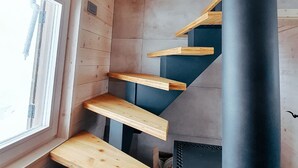 A wooden interior with a window, a black cylindrical object, and wooden steps. - Private Cottage - Active Regeneration and Relaxing Hollidays (Stahovica)