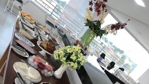 Ein reichhaltiges Buffet mit verschiedenen Früchten, darunter Wassermelone, Bananen und Äpfel, sowie eine Blumenvase.