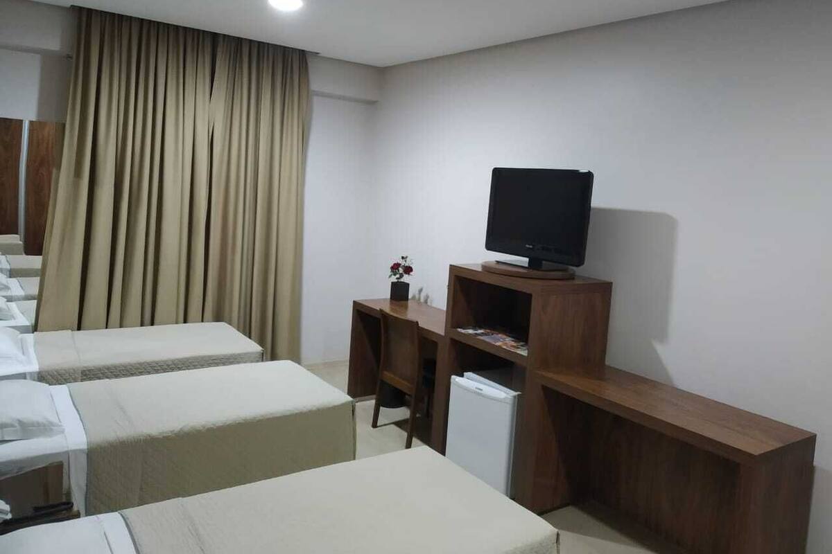A hotel room with a bed, a desk, a television, and a small refrigerator.