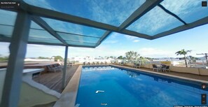 A swimming pool with a glass roof, surrounded by lounge chairs and a view of the cityscape. - Boa Vista Park Hotel (Jaraguá)