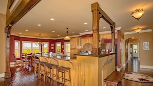 Une cuisine avec des tabourets de bar en bois, un four encastré et une grande fenêtre.