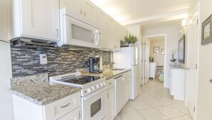 A modern kitchen with white cabinets, a built-in microwave, a gas stove, and a stainless steel range hood. - Oceanfront, Pet-Friendly Condo with Private Balcony! (St. Augustine)