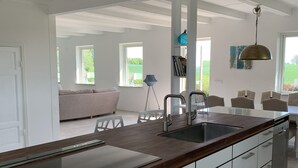 Una cocina moderna con una isla grande, armarios blancos y vistas al exterior.