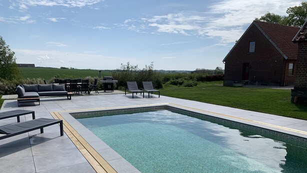 Una piscina rectangular con agua cristalina, rodeada por una terraza de baldosas.