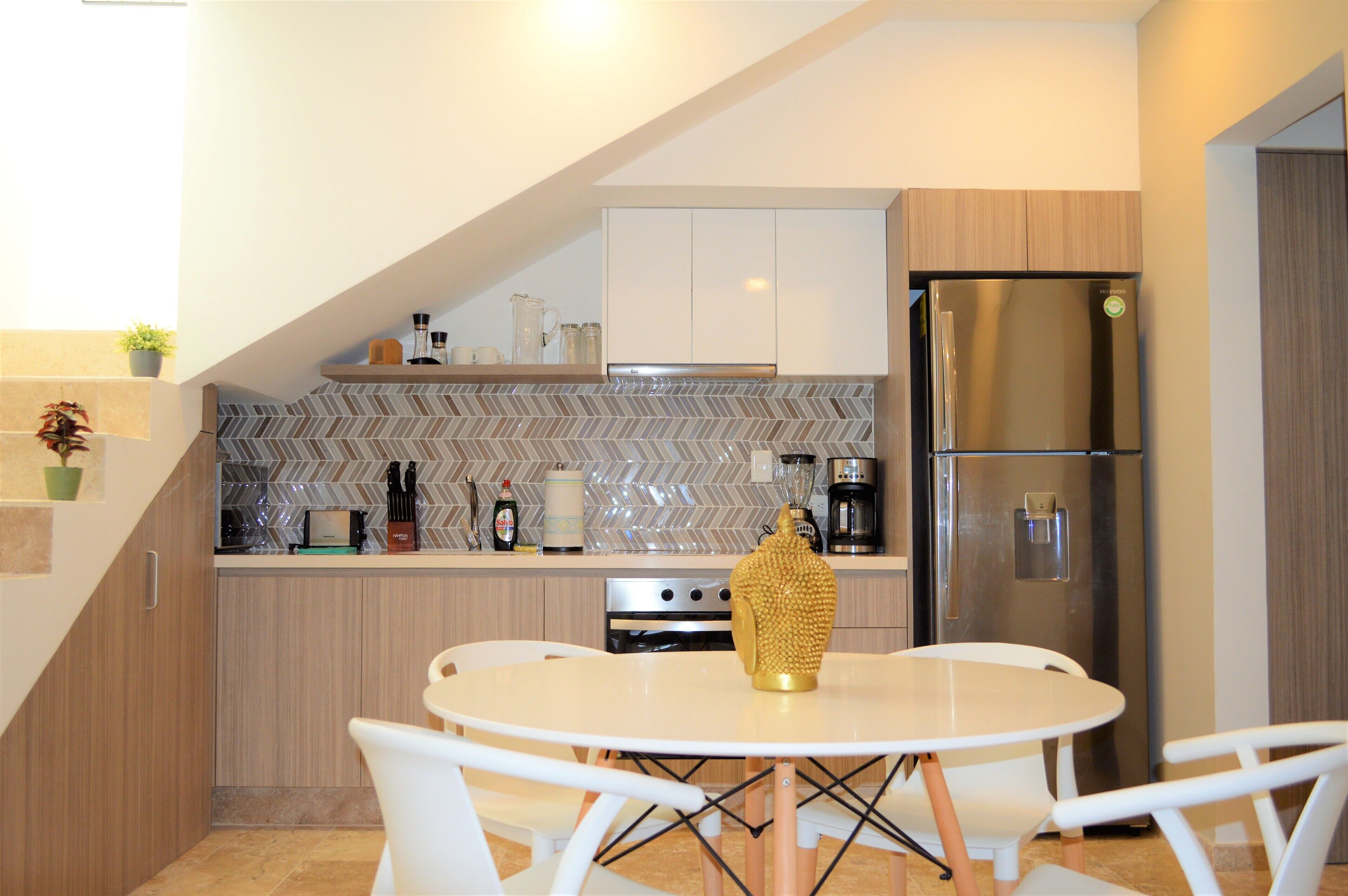 A modern kitchen with a herringbone tile backsplash, stainless steel appliances, and a white dining table with chairs.