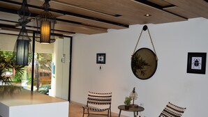 A modern interior with a wooden ceiling, two striped chairs, a round table, and hanging plants. - Pura Playa 501 by Riviera Rentals (Playa del Carmen)