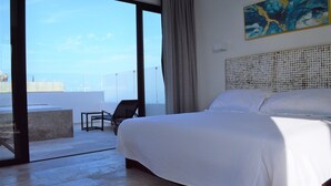 A hotel room with a large bed, a view of the sea, and a balcony with a chair. - Pura Playa 501 by Riviera Rentals (Playa del Carmen)