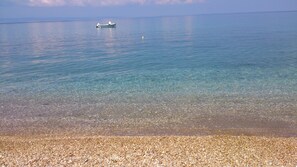 A calm sea with a boat anchored in the distance. - Olive house (Nikiti)
