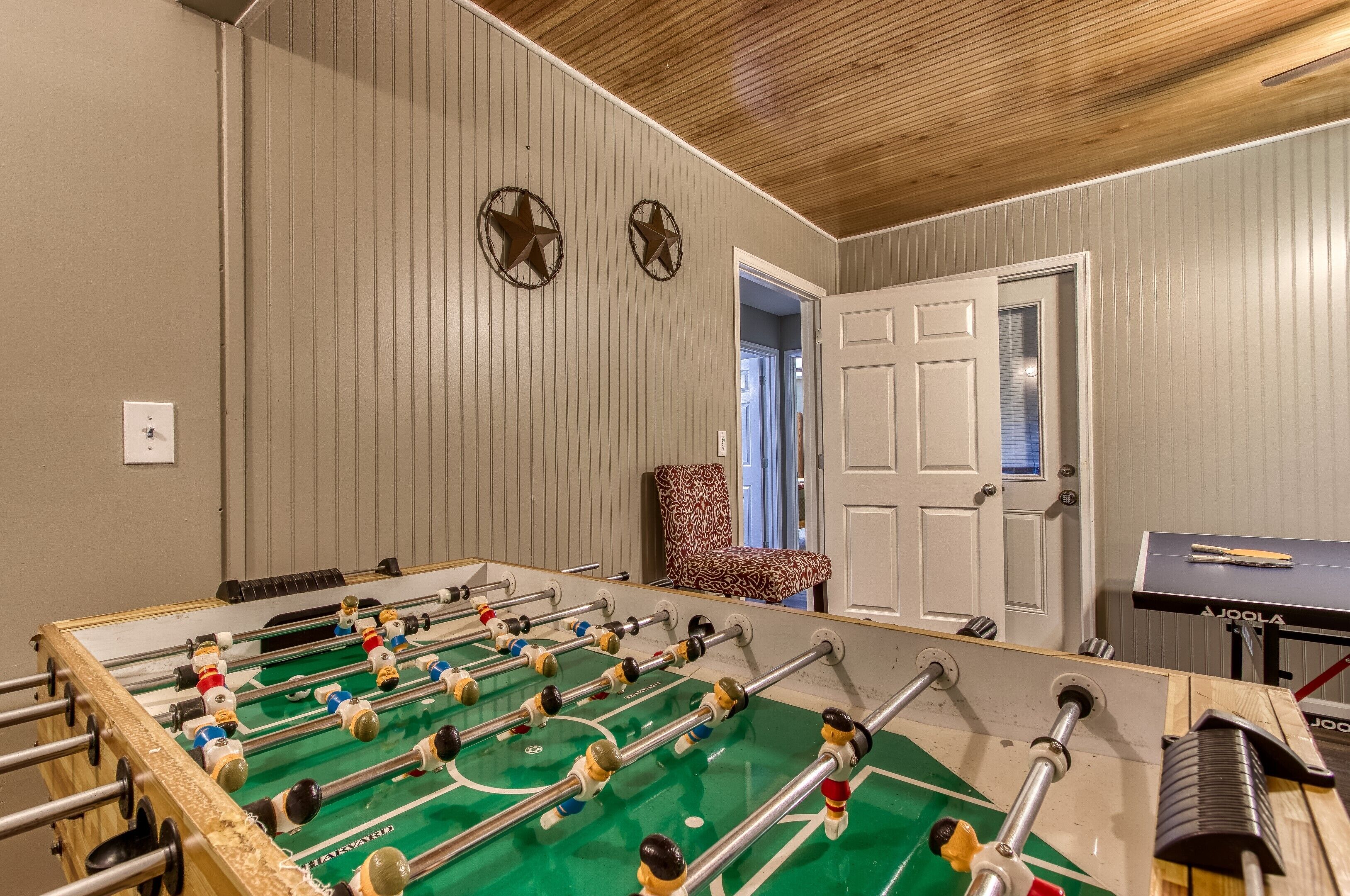 A foosball table in a room with wooden paneling and a door.