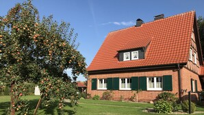 A house with a red-tiled roof, green shutters, and a well-maintained lawn.