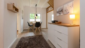 A modern kitchen with a dining area, wooden cabinets, a rug, and artwork on the wall.