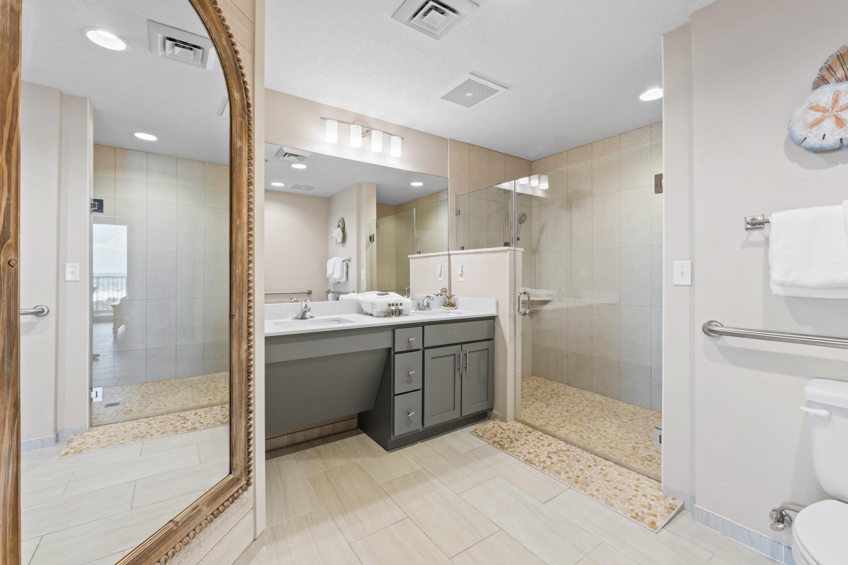 Un baño moderno con un espejo grande, ducha y retrete.