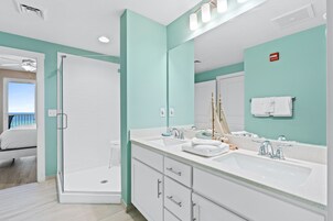 A modern bathroom with a glass shower enclosure, two sinks, and a large mirror.