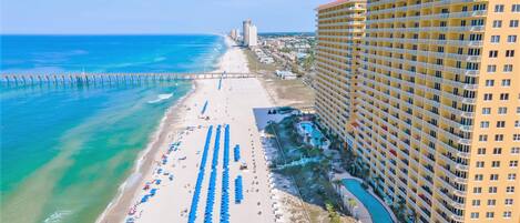 A high-rise hotel with a beach view, multiple balconies, and a pool area.