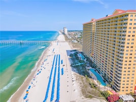 A high-rise hotel with a beach view, multiple balconies, and a pool area.
