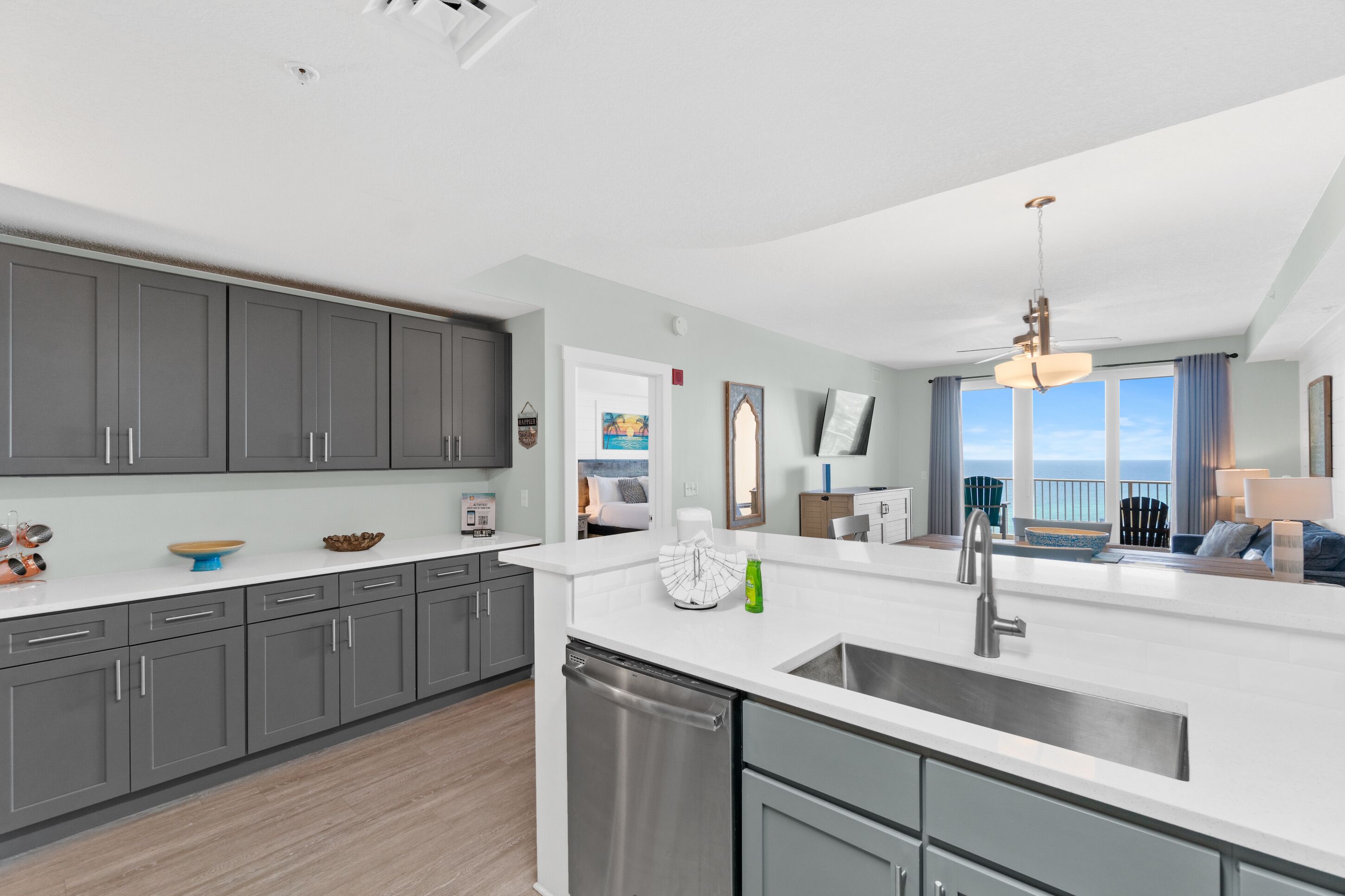 A modern kitchen with grey cabinets, a white countertop, and a built-in dishwasher.